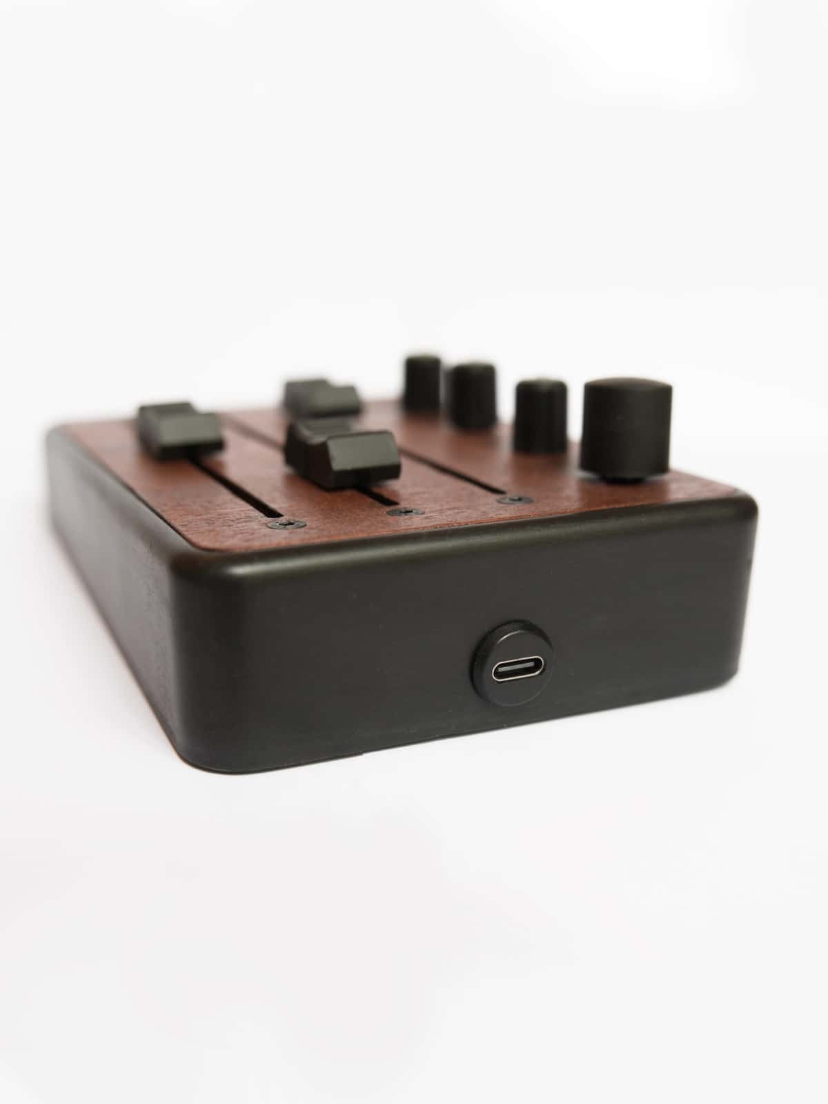 Brise MkII MIDI Controller seen from the side, with its USB-C port, black enclosure and mahogany top