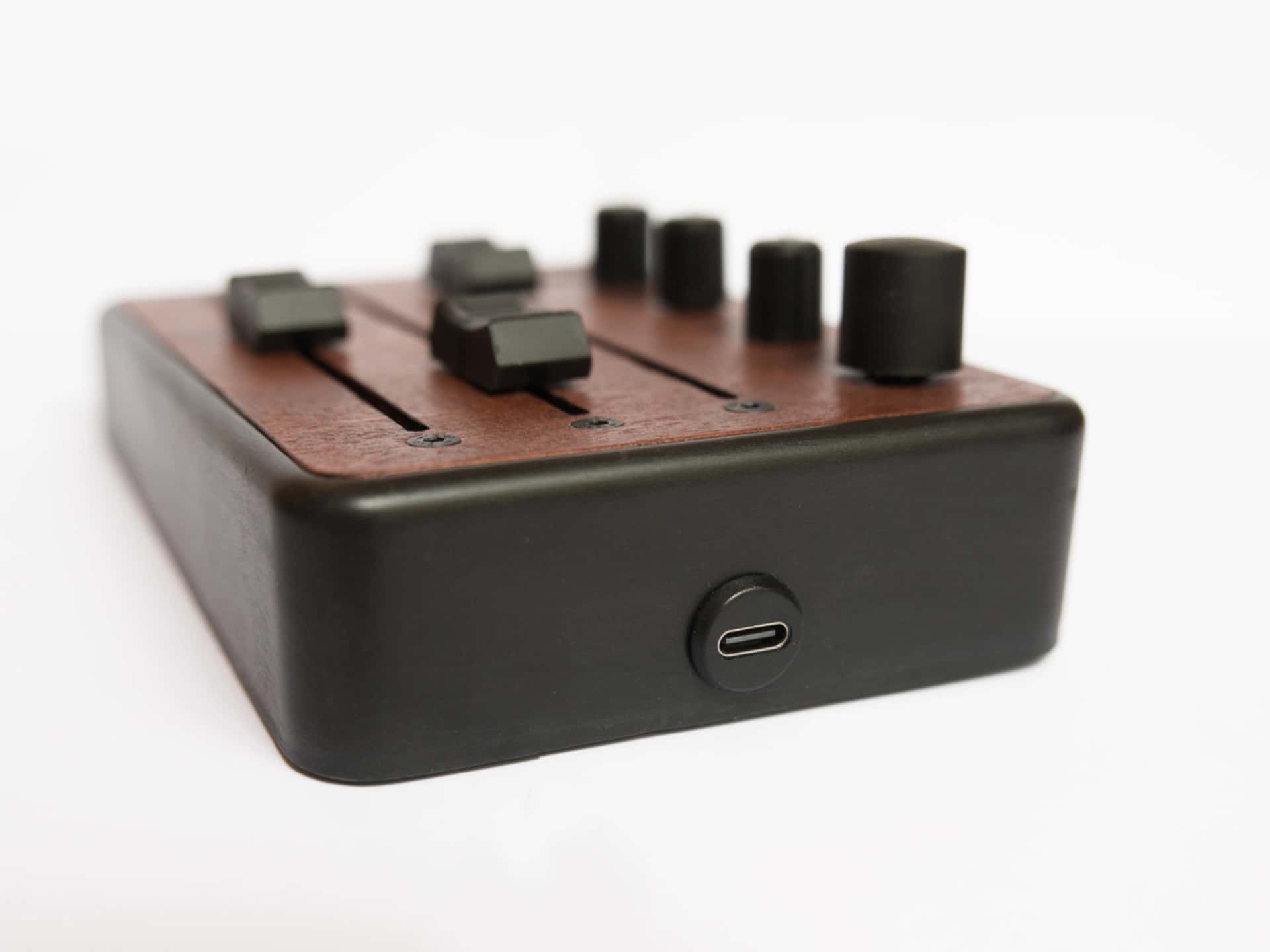 Brise MkII MIDI Controller seen from the side, with its USB-C port, black enclosure and mahogany top