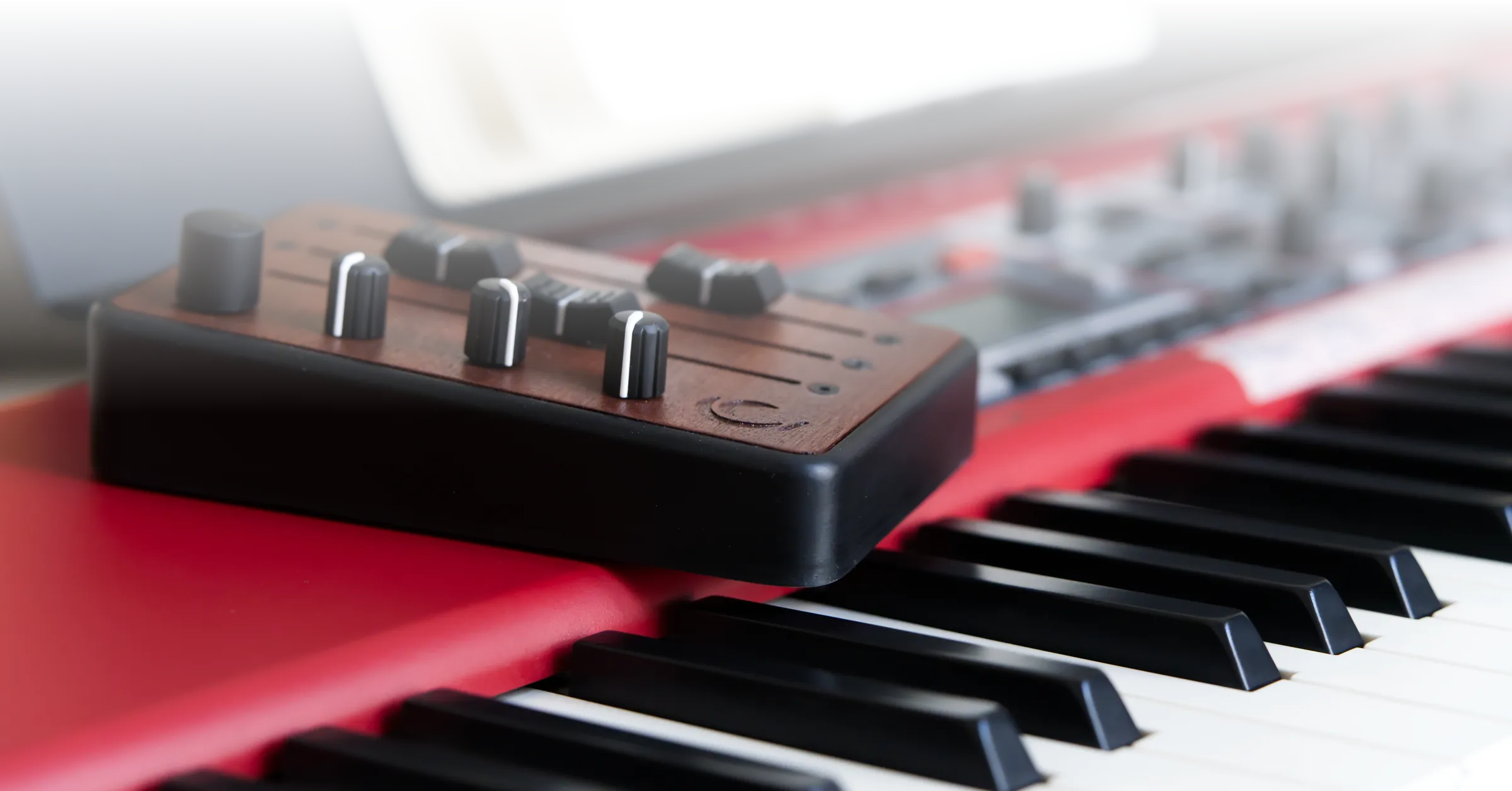 Brise MkII MIDI Controller on a red stage piano, with close up on the knobs, rotary encoder and faders
