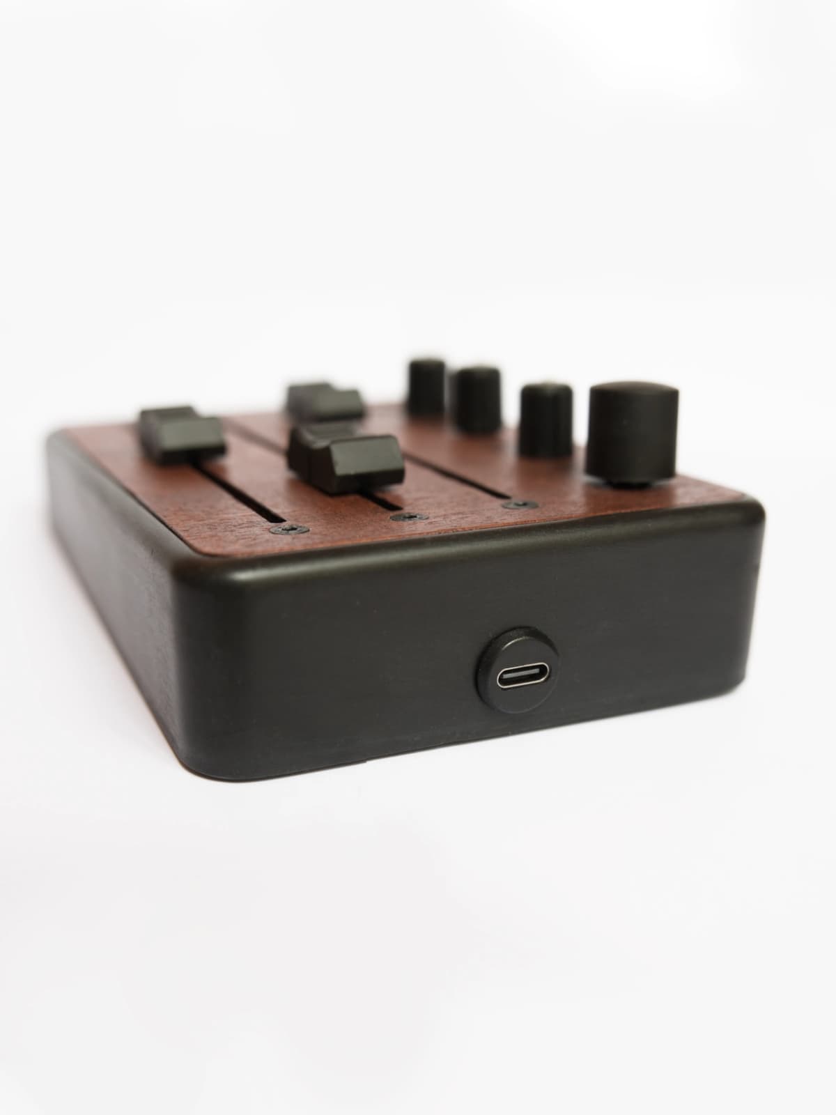 Brise MkII MIDI Controller seen from the side, with its USB-C port, black enclosure and mahogany top