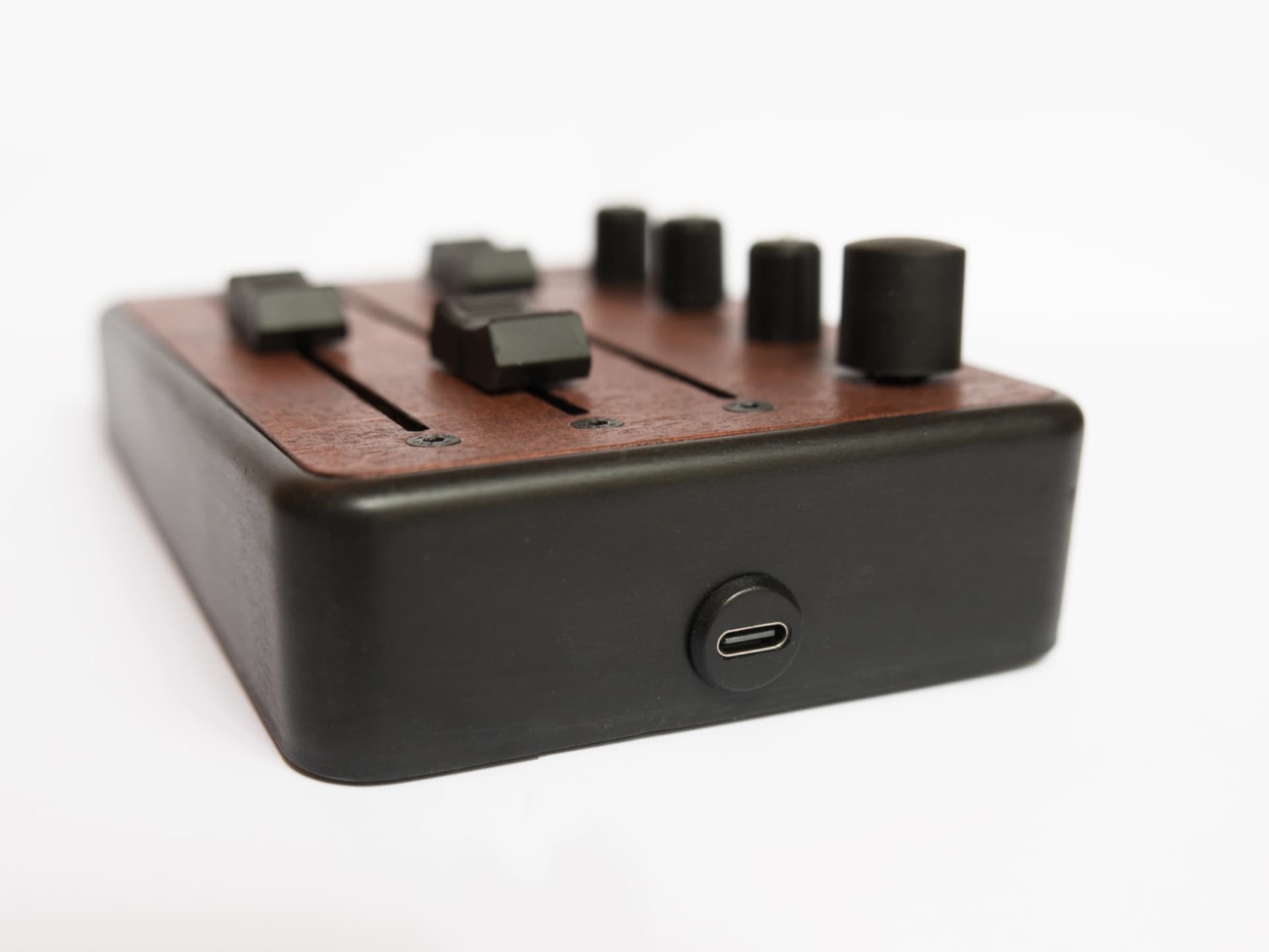 Brise MkII MIDI Controller seen from the side, with its USB-C port, black enclosure and mahogany top